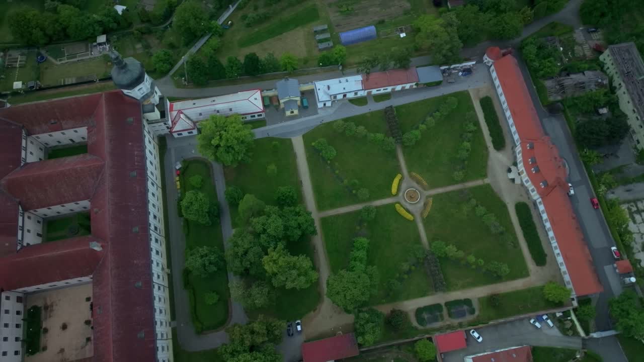 Aerial view of the garden at Klášterní Hradisko, Olomouc, in spring during the evening. Blossoming greenery and historic architecture illuminated by soft light.