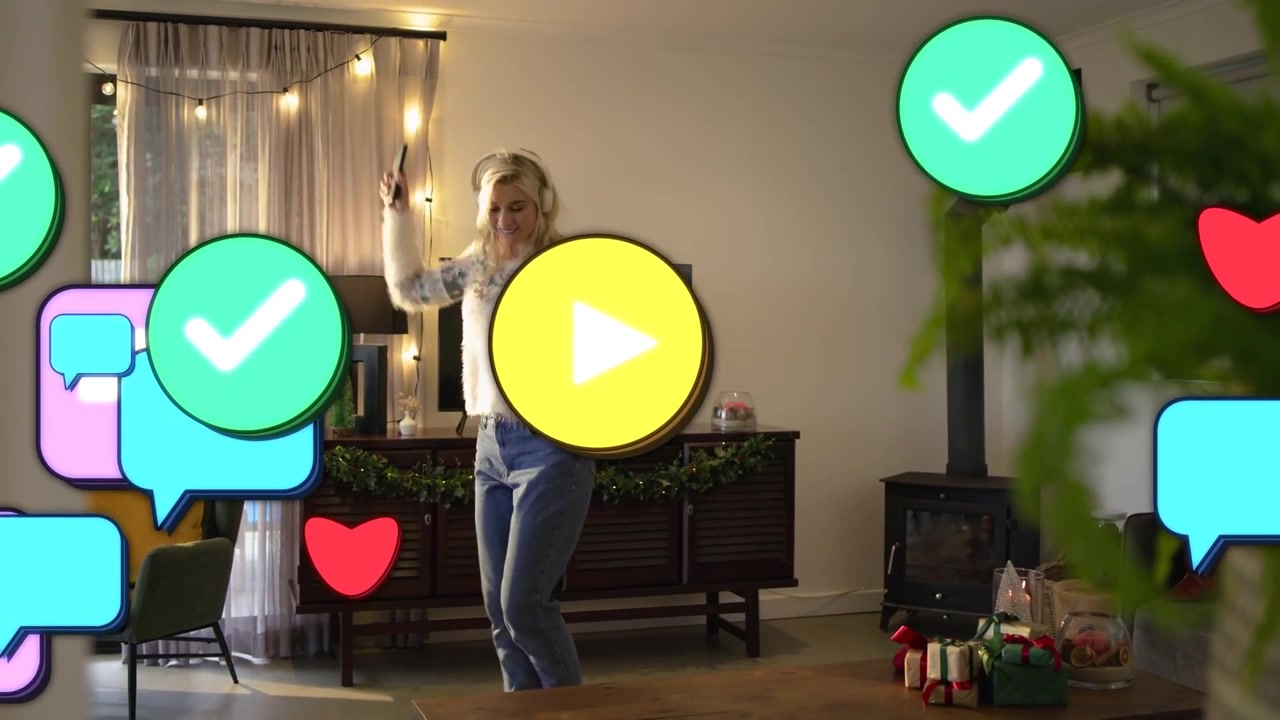 Video vertical: Mujer bailando con auriculares al ritmo de la música, grabándose con el teléfono en casa para conseguir 'me gusta', con un suéter.