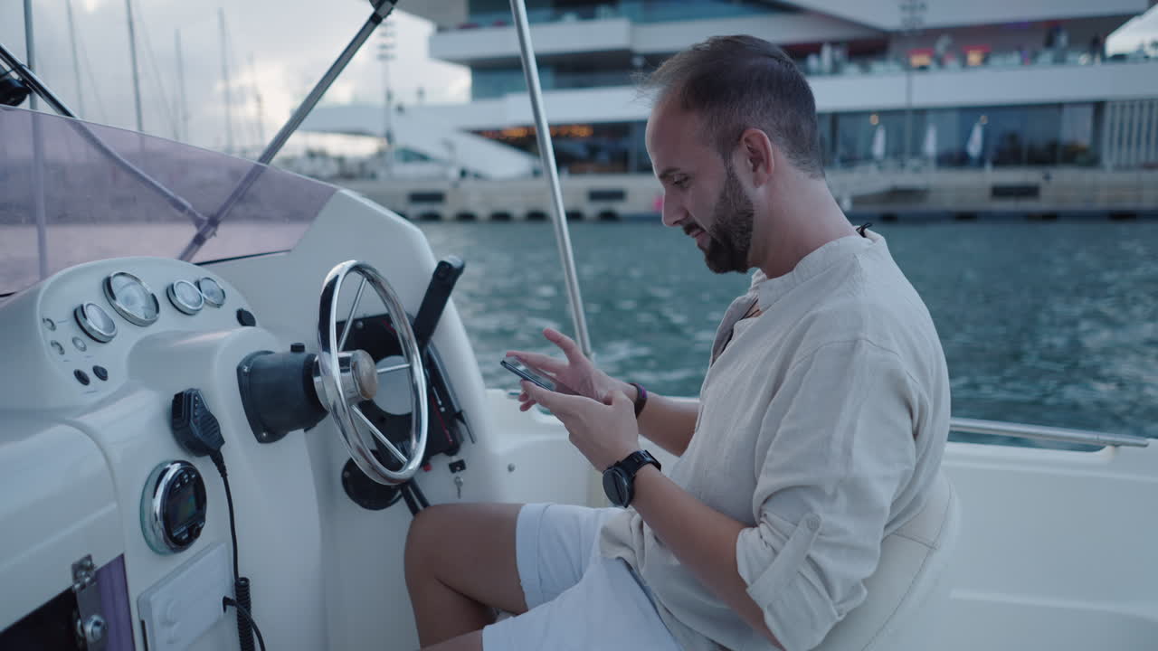Man using smartphone on a boat at a marina