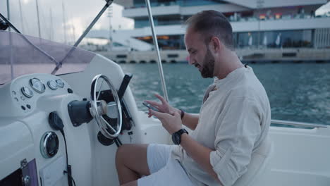 man using smartphone on a boat at a marina