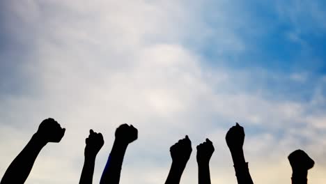 silhouetted fists raised in protest against a blue sky