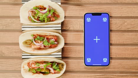 tacos on a wooden table with a smartphone