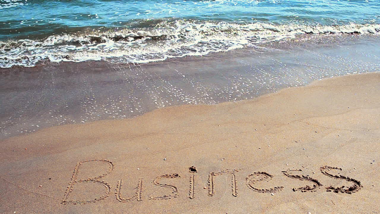 Iscrizione 'business' sulla sabbia. Riprese sulla spiaggia.