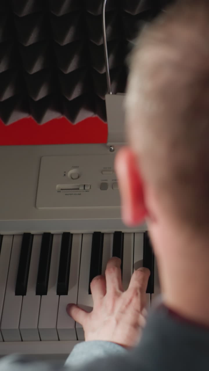 vista trasera de un hombre sentado en un piano blanco, sus manos tocando con gracia las teclas, en contra de un fondo de espuma acústica negra