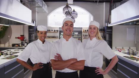 Chefs-Multiétnicos-Vestidos-De-Chefs-Blancos-En-La-Cocina-De-Un-Restaurante-Mirando-A-La-Cámara-Y-Sonriendo