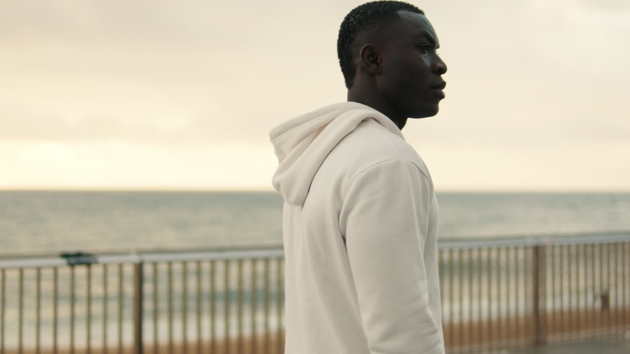 Ung sort mand går tur på promenade ved havet
