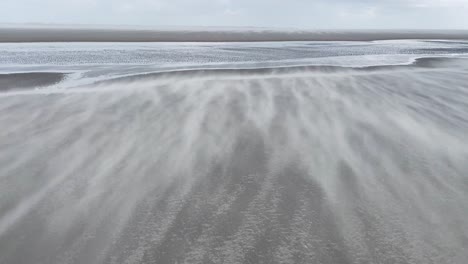 tiro ancho de pequeños granos de arena volando sobre la playa debido al fuerte viento en el mar del norte