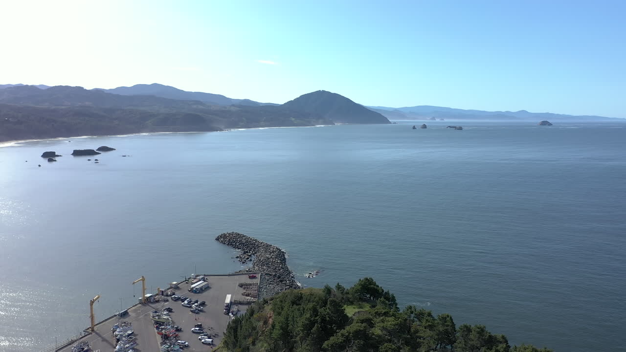 un dron volando sobre una colina en port orford, oregon, revelando el puerto del muelle seco.