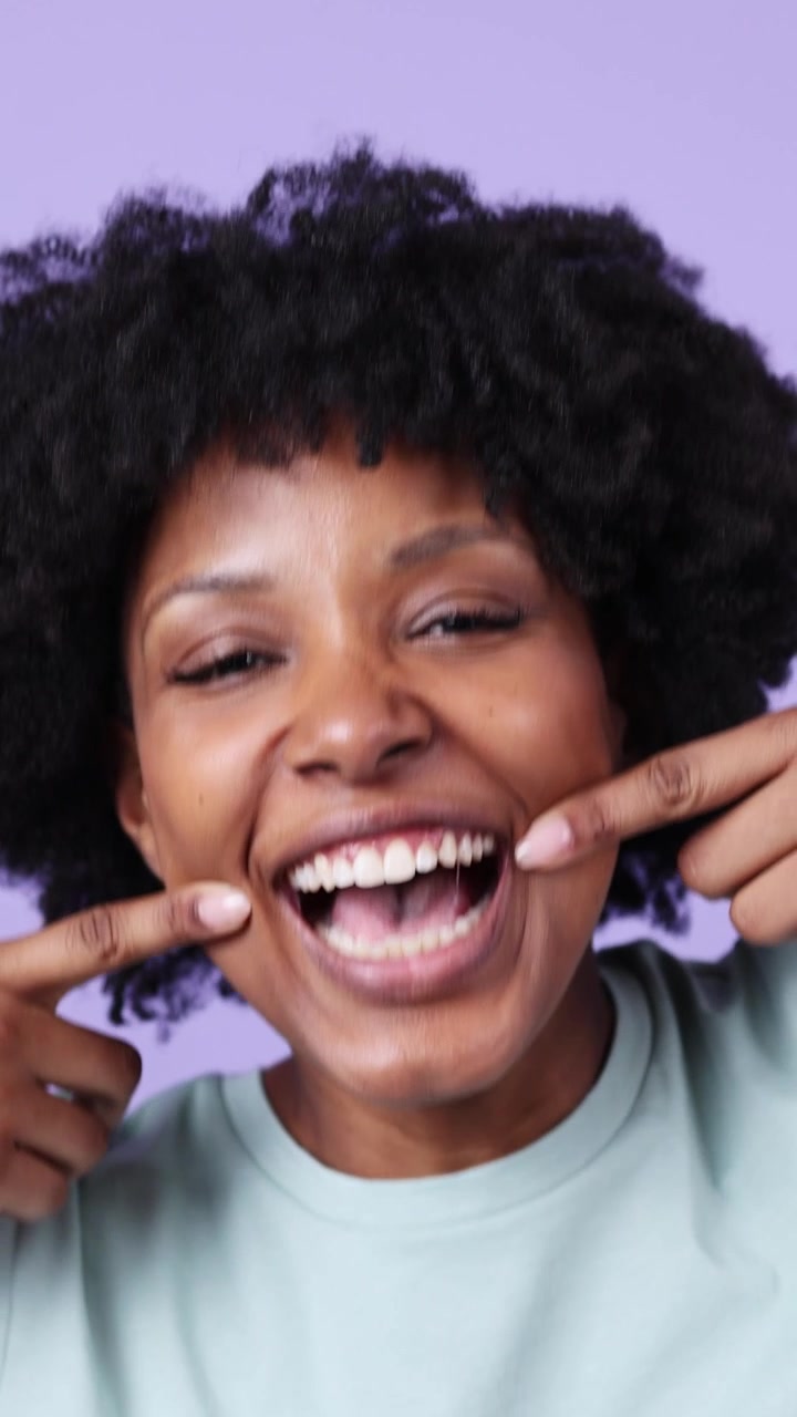 Young Black Woman Stretching Mouth to Show Teeth and Smiling