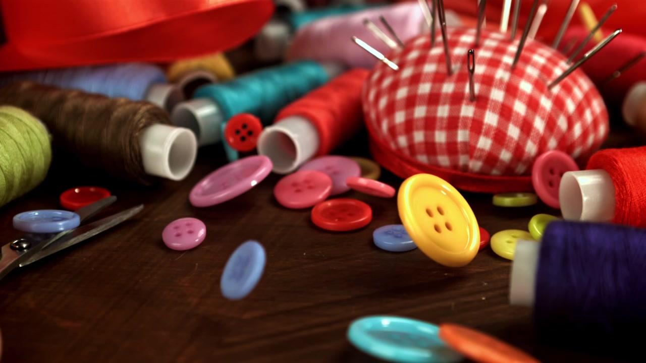 Colorful Buttons Falling onto a Wooden Table with Sewing Supplies