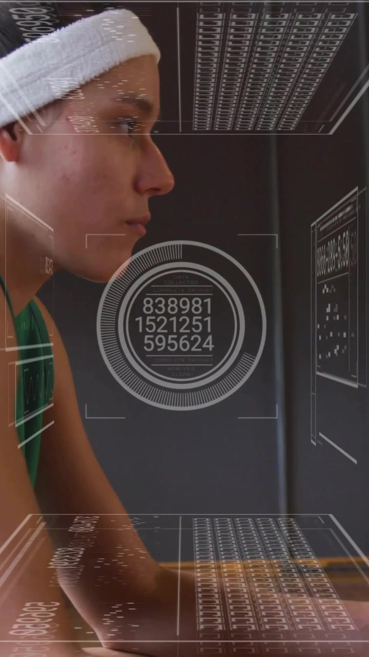 Woman sitting in profile at desk, typing on keyboard and activating HUD analyzing fitness metrics