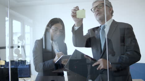 business leader and his assistant writing and sticking notes