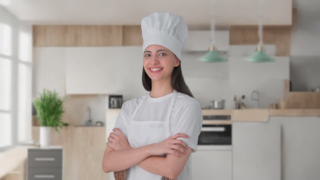 Ritratto di felice chef professionista indiana in piedi con le braccia incrociate