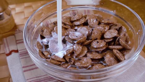 copos de chocolate crujientes en un tazón para un delicioso desayuno matutino con leche. cámara lenta con toma de seguimiento de rotación.
