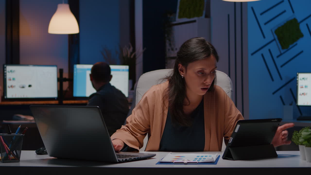 Workaholic focused businesswoman analysing financial graphics on tablet