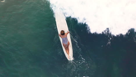 toma aérea de una surfista remando una ola en una tabla de surf