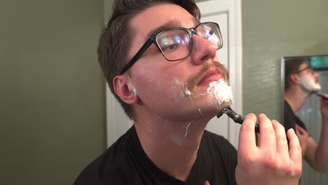 caucasian man with mustache shaving his beard