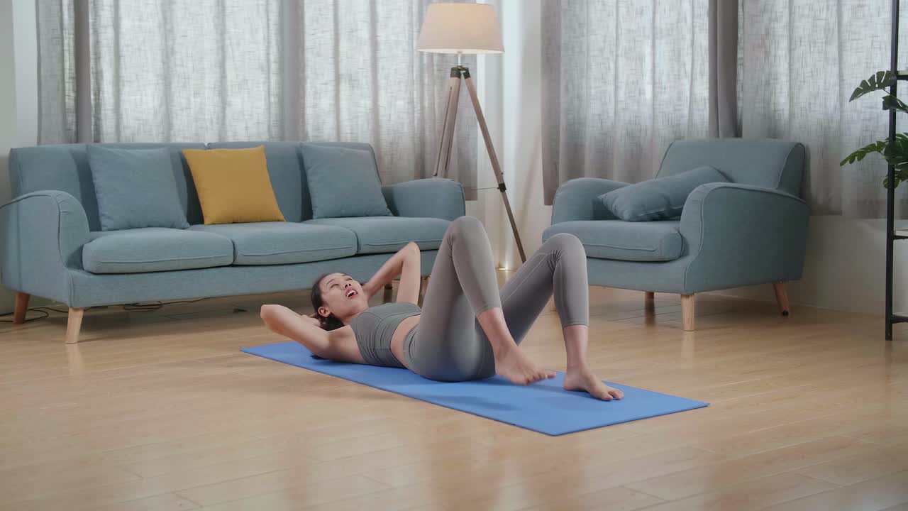 joven atleta asiática con ropa deportiva haciendo ejercicios de crisscross crunch mientras entrena en casa