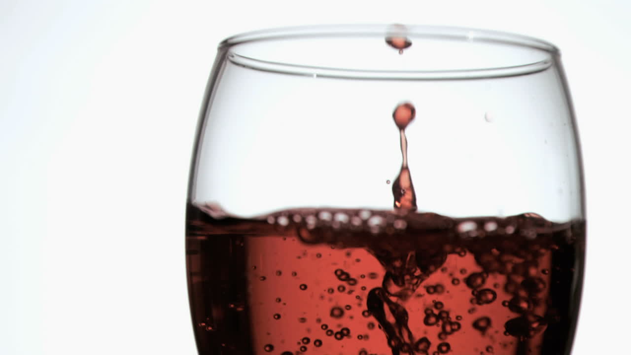 vino rojo en súper cámara lenta goteando en un vaso