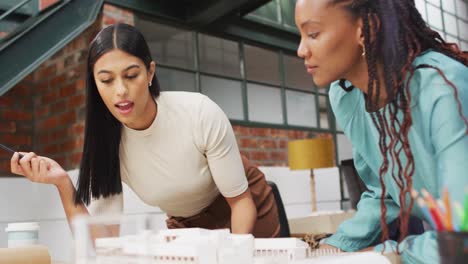 Happy-diverse-female-architects-looking-at-architectural-models-at-office