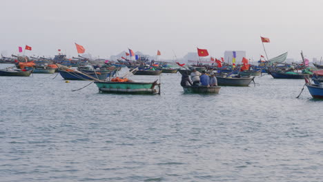Dolly-shot-of-fishermen-navigating-through-the-docked-sailboats-with-flags-in-Da-Nang