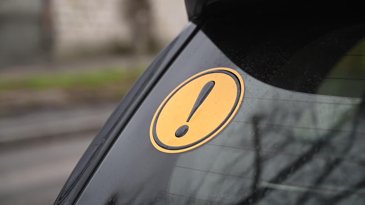 Beginner driver yellow round sign on a car. Traffic on background