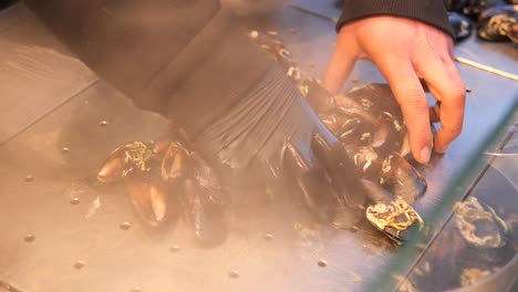 steaming fresh mussels in a metal tray at a market