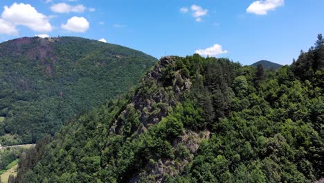 cross at the edge of the rocky cliff and lush green forest at apuseni mountains in romania