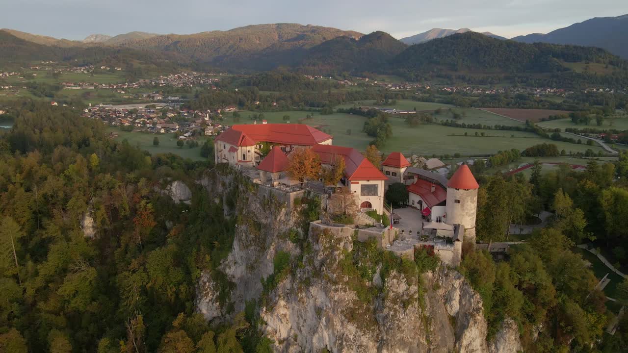 Veduta aerea del Castello di Bled su una rupe con montagne sullo sfondo