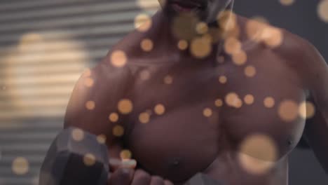 Spots-of-light-against-african-american-fit-man-working-out-with-dumbbells-against-red-background