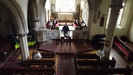 tiro de horca de un vicario de pie en la parte delantera de una iglesia vacía en inglaterra