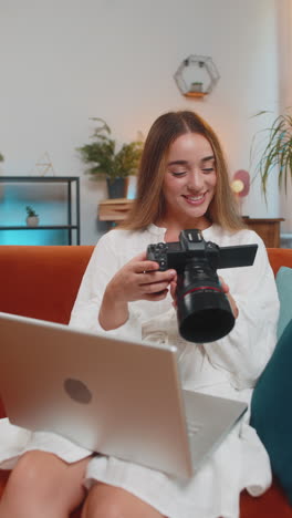 mujer feliz fotógrafa con portátil y cámara digital mirando la pantalla eligiendo fotos en casa