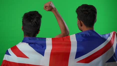 retroceso positivo amigos de oriente medio gestando éxito apoyando al equipo de fútbol británico en pantalla verde. felices aficionados al deporte satisfechos envueltos en la bandera nacional regocijándose gol hablando sonriendo.