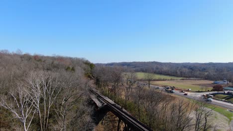 aerial shot of railroad tracks winding out of a forest and on to the pope lick trestle in louisville kentucky