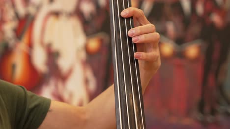 left hand of a man playing the strings of a double bass