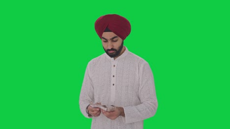 sad sikh indian man counting money green screen