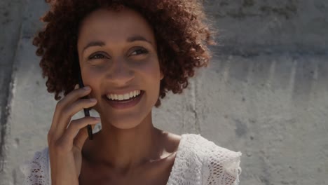 Front-view-of-young-African-american-woman-talking-on-mobile-phone-at-beach-in-the-sunshine-4k