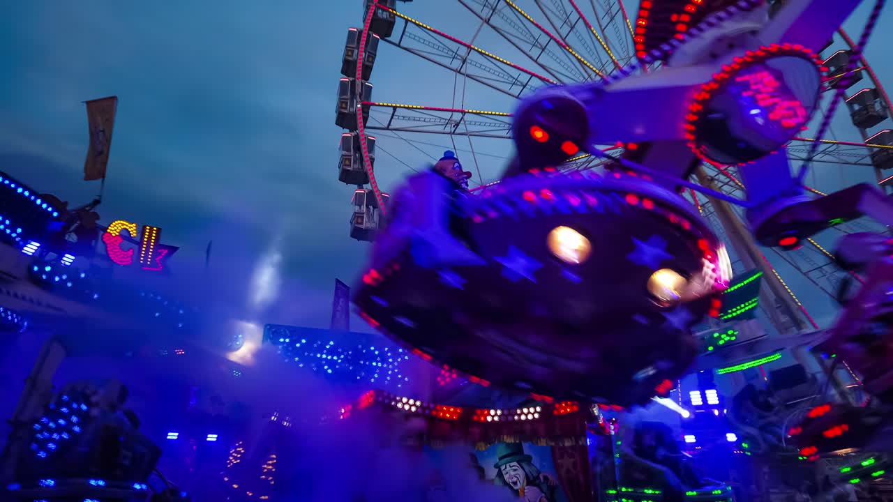 Evening Motion Time Lapse of Rotating Funfair Rides at Illuminated Amusement Park