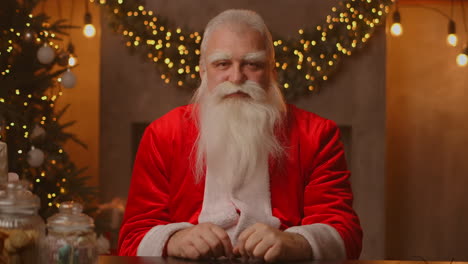 headshot looking at the camera happy old bearded santa claus wearing costume and waving hand video calling recording video merry christmas greeting face camera view. high quality 4k footage