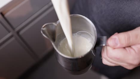 Barista-Gießt-Milch-In-Eine-Milchkanne-Als-Vorbereitung-Für-Eine-Milchkaffeevariation