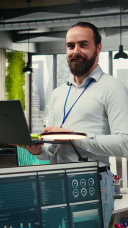 vertical video male team leader monitoring analytics on a laptop in co working space
