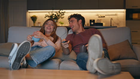 relaxed partners chilling sofa watching tv at evening. family time together