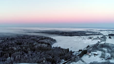 aerial view of snowy village and forest with pastel colors of horizon