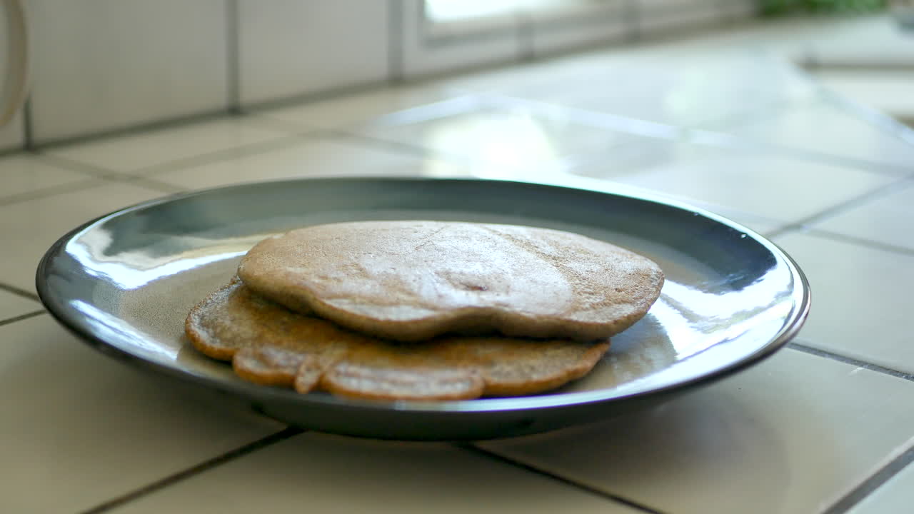 выкладывание горячего цельнозернового блина со сковороды на тарелку во время завтрака на кухне