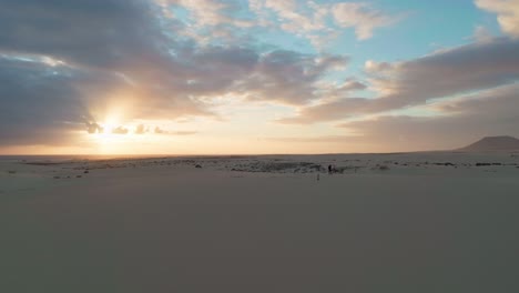 Eine-Person-Geht-Bei-Sonnenaufgang-Auf-Fuerteventura-Auf-Den-Sanddünen-Spazieren