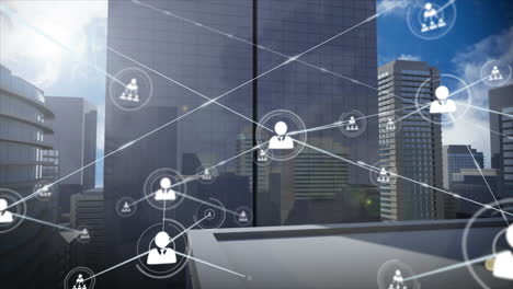 animation of network of profile icons and light spots against aerial view of tall buildings