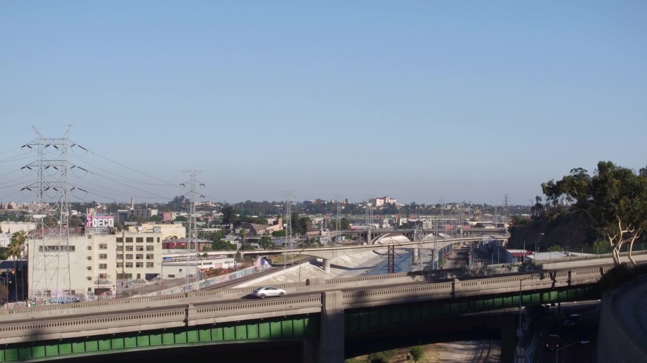 Ripresa aerea con drone che si alza sopra un ponte con auto che attraversano il fiume LA a Los Angeles, California