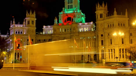 illuminated grandeur of a historic building, likely a palace or government building city council with vibrant spanish flags and a fountain statue at the forefront during the night