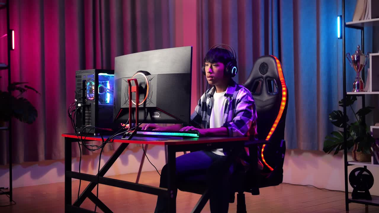 심각한 아시아 십대 소년 게이머가 컴퓨터에서 비디오 게임을 하고 있습니다.