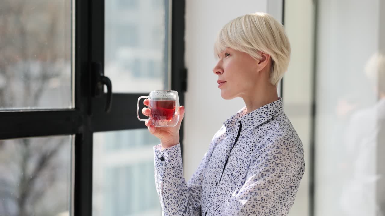 Woman drinking tea and looking out the window